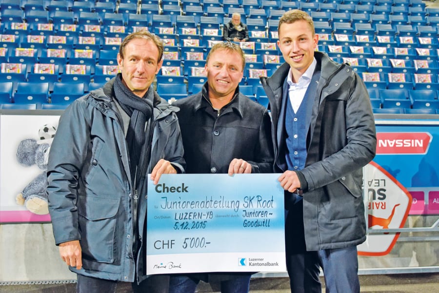 Alexander Wismer (links) überreicht SK-Root-Präsident Roger Bühler den Check über 5000 Franken. Rechts im Bild der verletzte FCL-Spieler Remo Arnold. (Bild FCL/Tino Meienberger)